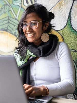 A girl sitting and smiling at her computer.