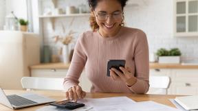 Person using their phone and a calculator to do finances.