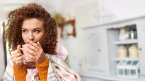 Girl wrapped up in a blanket with a coffee mug. 