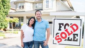 couple standing by a sold sign