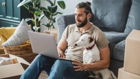 Man and dog sitting on the couch with a computer