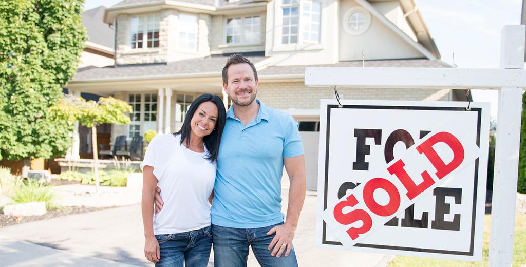 couple standing by a sold sign