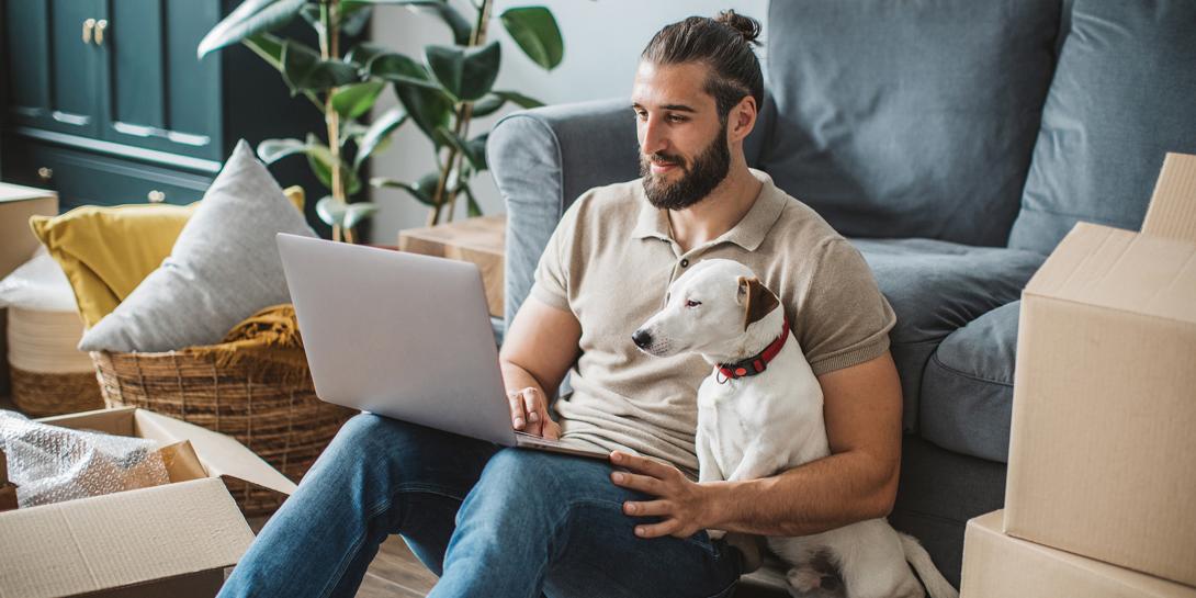 Man and dog sitting on the couch with a computer